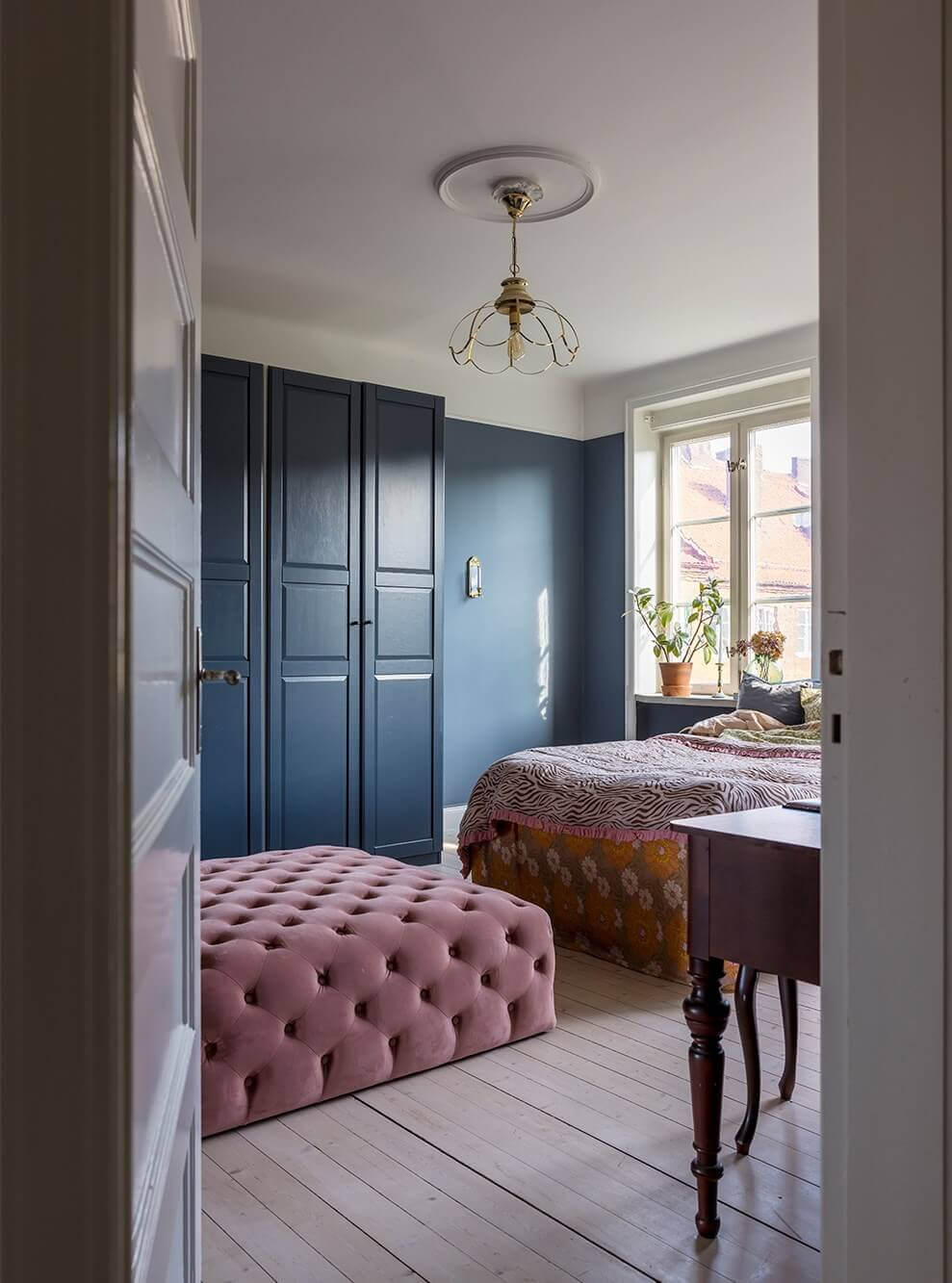 A Spacious Nordic Apartment with a Wonderful Color Palette 15 dark blue bedroom with large purple ottoman