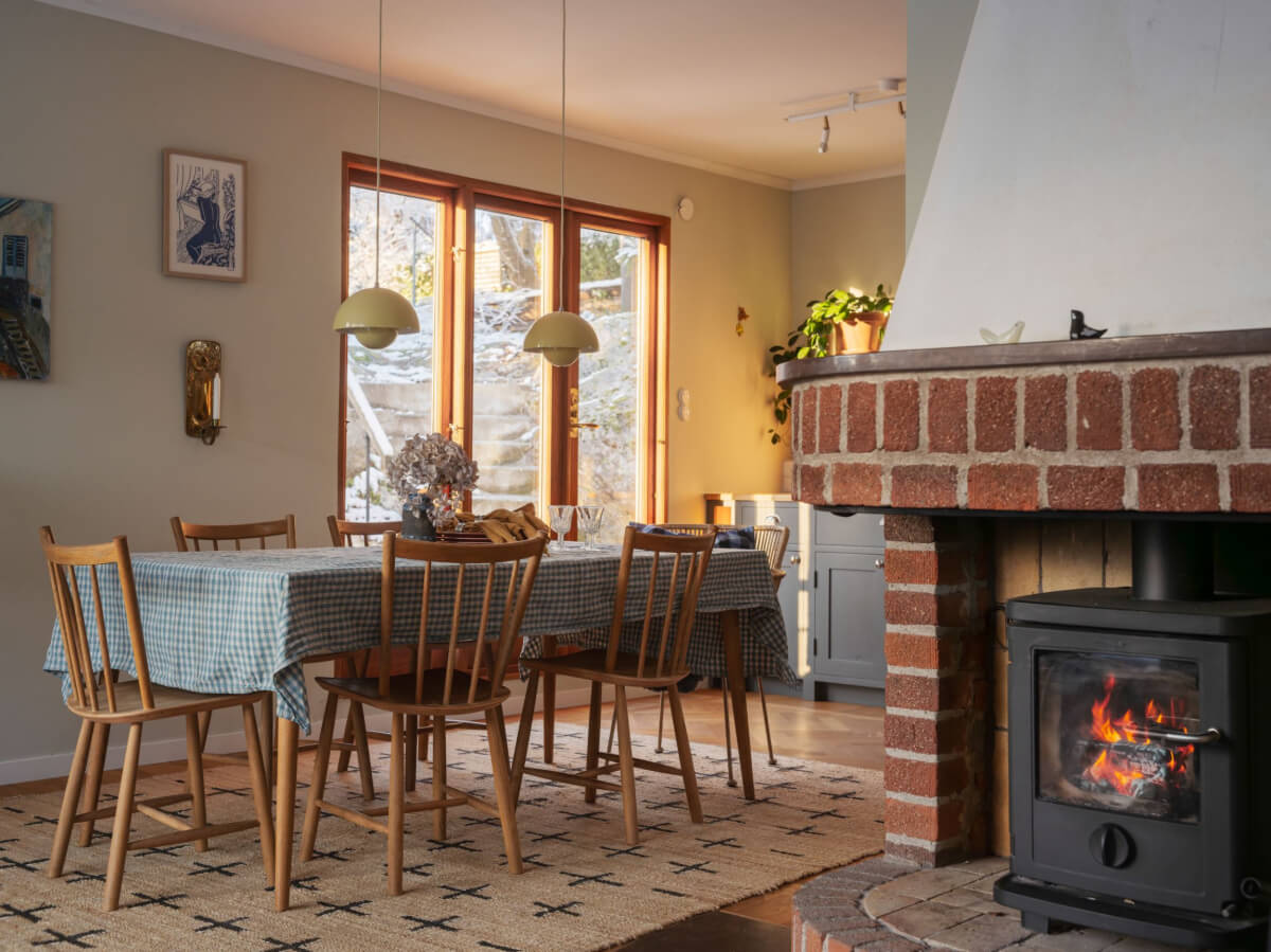 A Beautiful Midcentury Family Home South of Stockholm 9 dining table and brick fireplace with wood burner