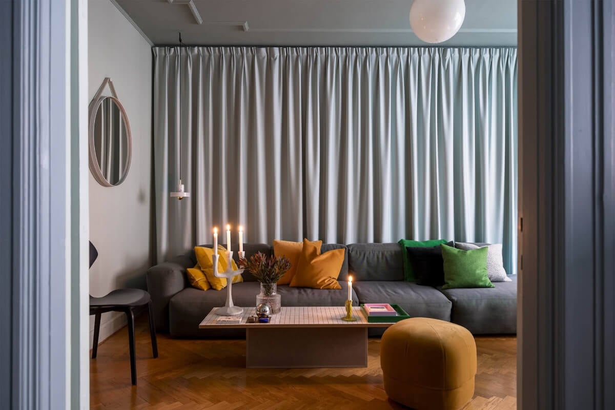 An Interior Designer's Moody Apartment with Period Features 2 gray living room with curtain behind couhc and ochre yellow color accents