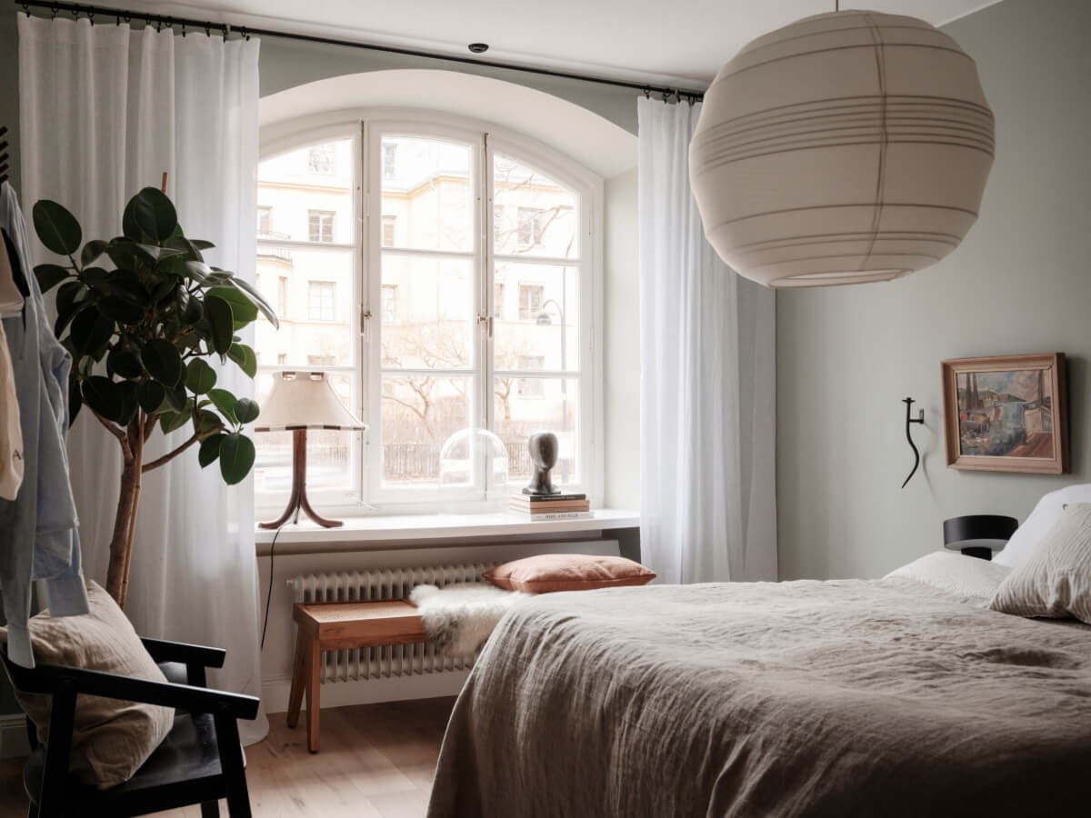 A Calm and Contemporary Apartment in a Former Office Space 16 gray scandinavian bedroom with arched window and large pendant