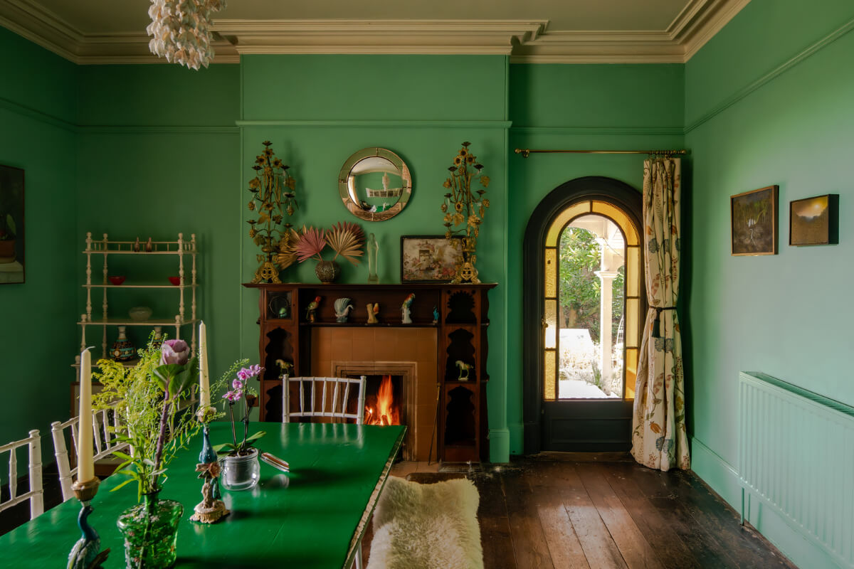 A Strong Color Palette in a Unique Country House in Cornwall 5 green dining room with green table and fireplace