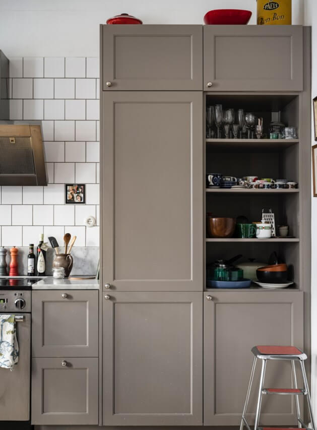 Muted Tones, Art, and Books in a Charming Stockholm Apartment 8 kitchen with brown gray cabinets white backsplash tiles