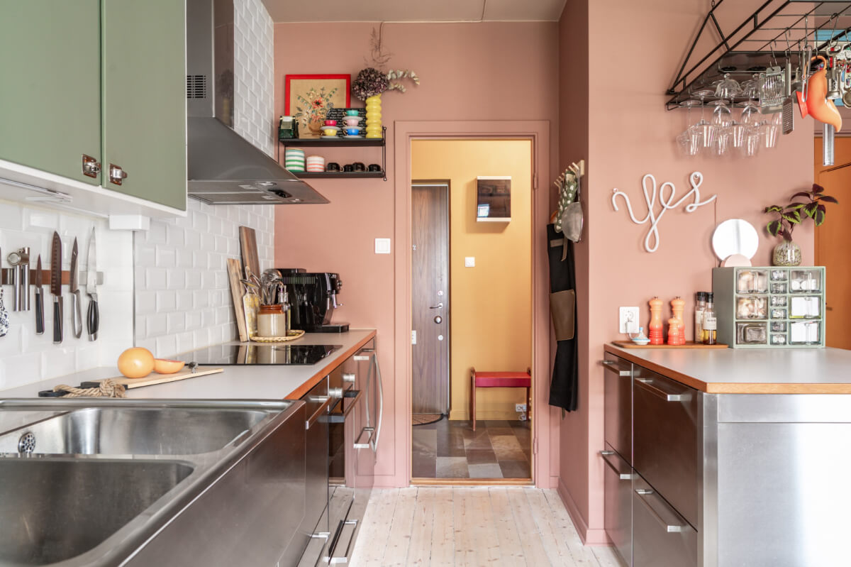 A Vibrant, Colorful Midcentury Apartment in Malmö 13 kitchen with earthy pink walls and green cabinet doors