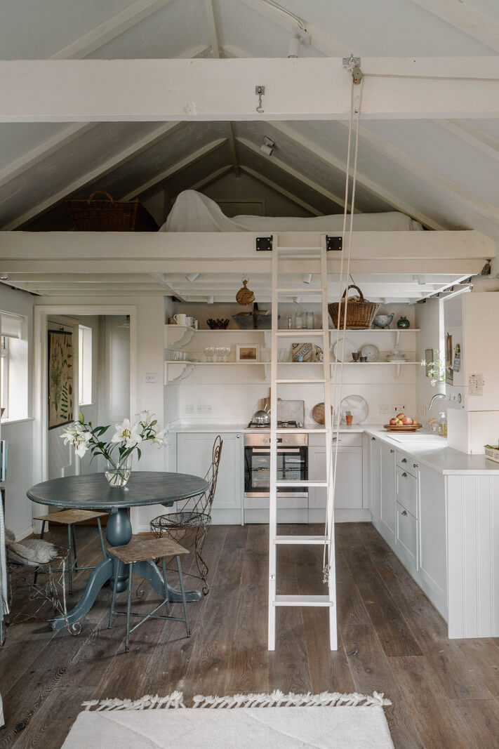 French and Midcentury Influences in a Charming London Studio Apartment 12 kitchen with open shelves round dining table and loft bed nordroom