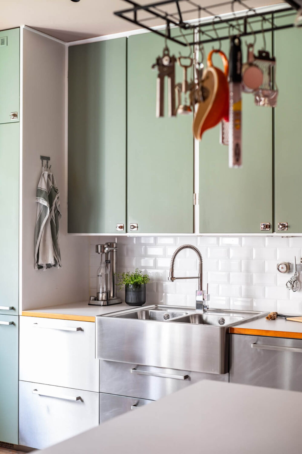 A Vibrant, Colorful Midcentury Apartment in Malmö 12 kitchen with stainless steel and green cabinets up to the ceiling