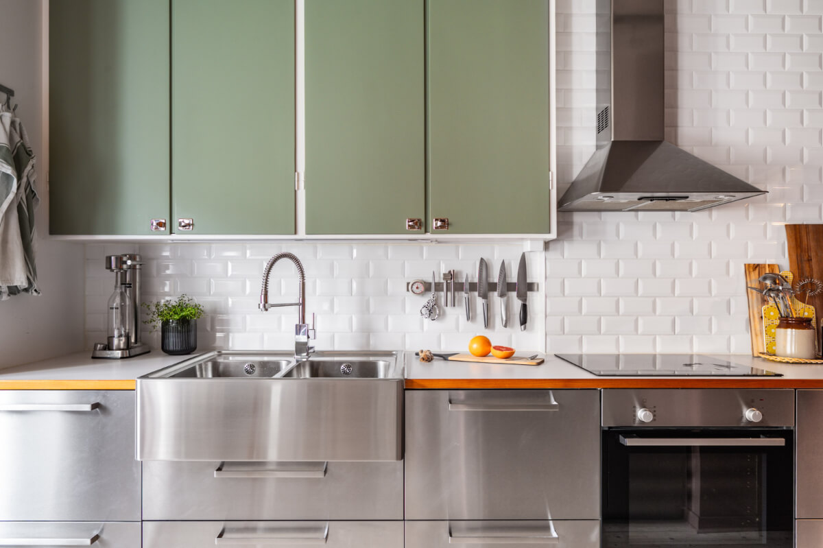 A Vibrant, Colorful Midcentury Apartment in Malmö 10 kitchen with stainless steel lower cabinets and green upper cabinets