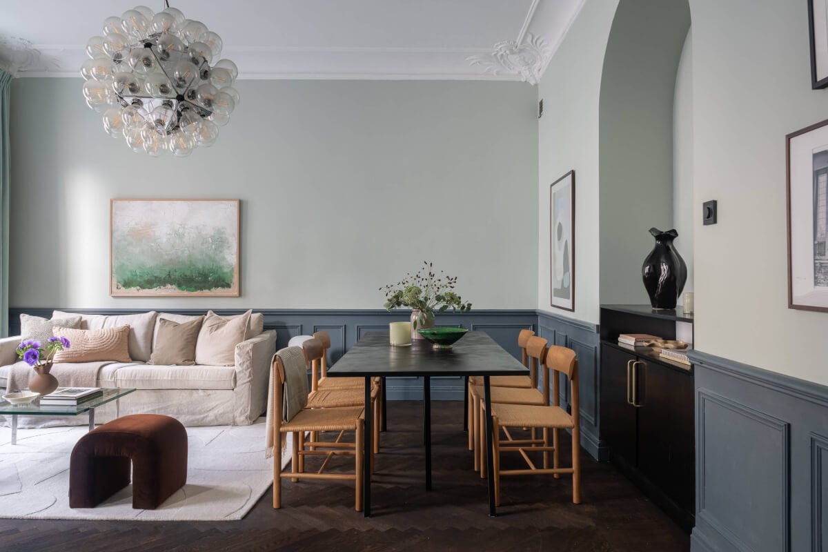A Moody Color Palette in a Stylish One-Bedroom Apartment in Stockholm 7 living room with dining table and dark wooden floor