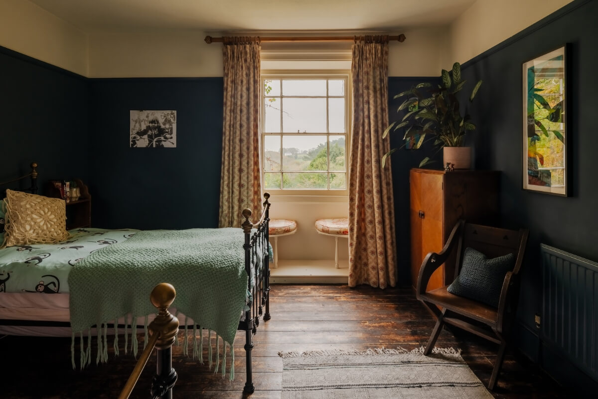 A Strong Color Palette in a Unique Country House in Cornwall 17 moody bedroom with dark walls and wooden floor
