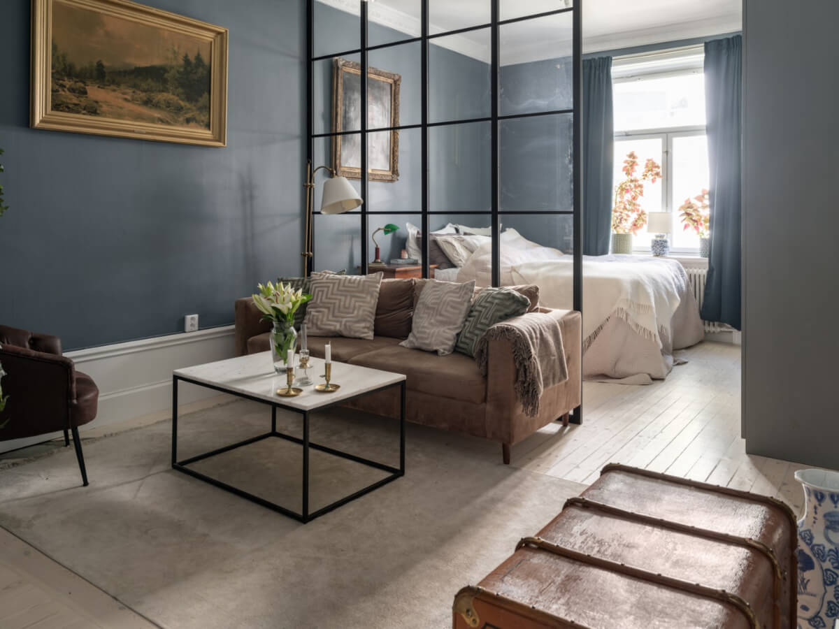 moody studio apartment with antique art and glass steel room divider nordroom