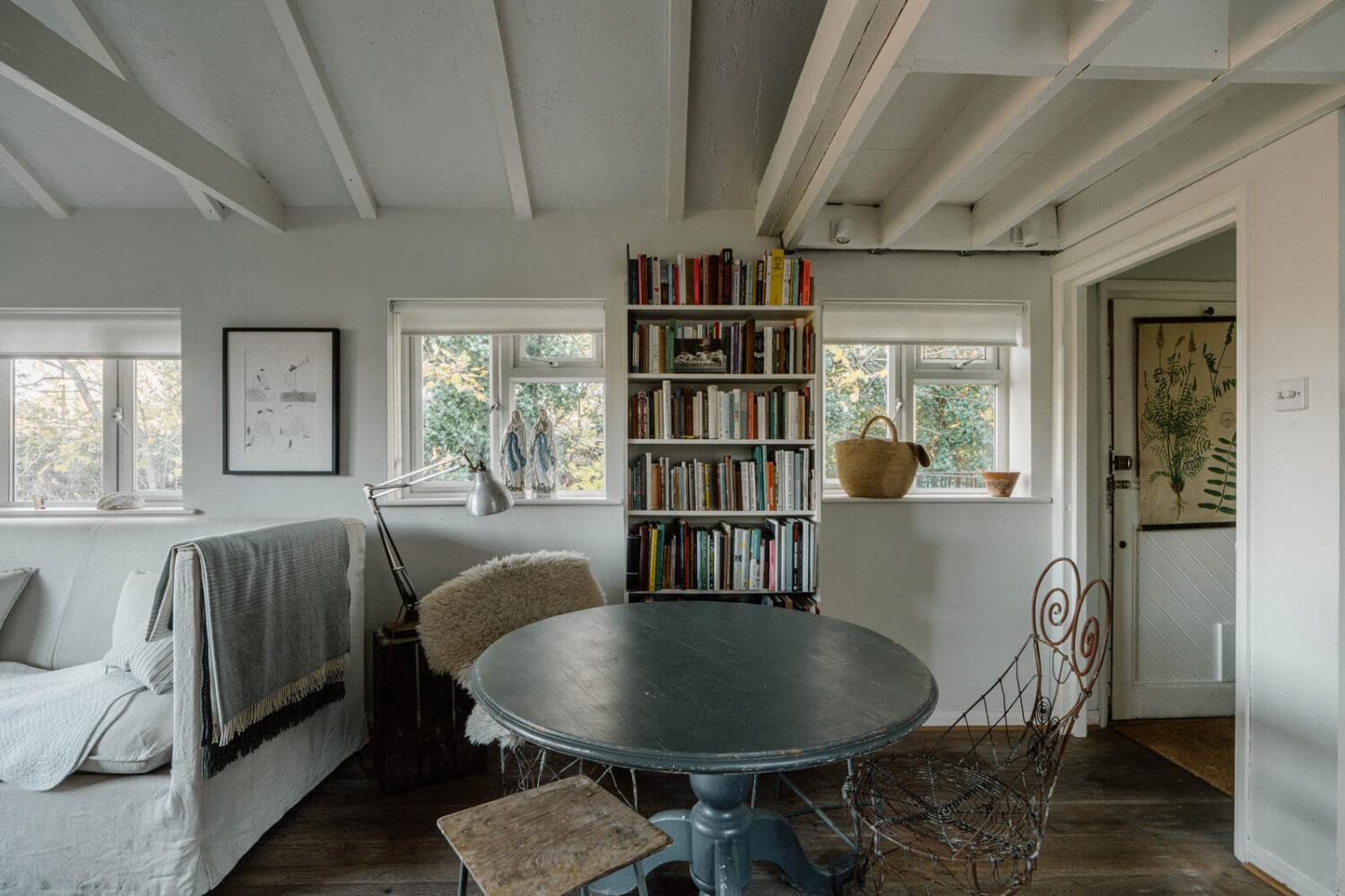 French and Midcentury Influences in a Charming London Studio Apartment 8 round dining table and bookshelves in london studio apartment