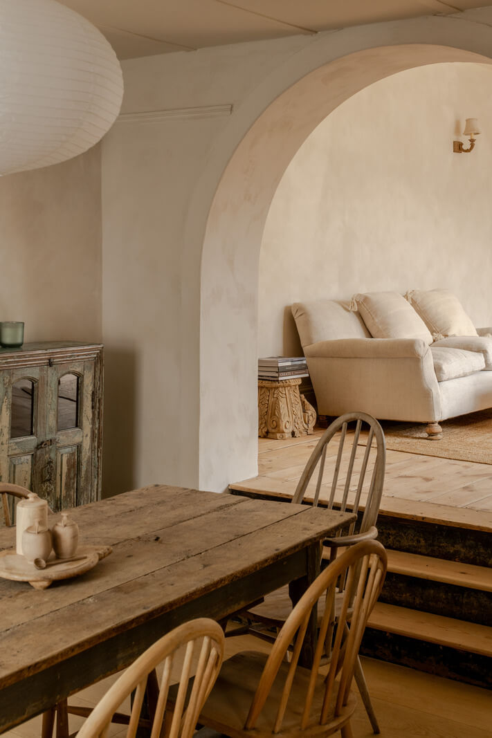 rustic table in dining room with arched opening to living room nordroom