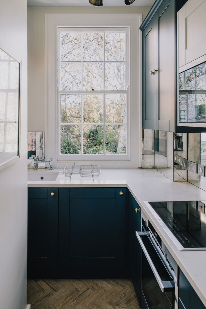 Why Everyone’s Adding Mirrors to Their Kitchens (And You Should Too) 3 small kitchen with dark blue cabinets
