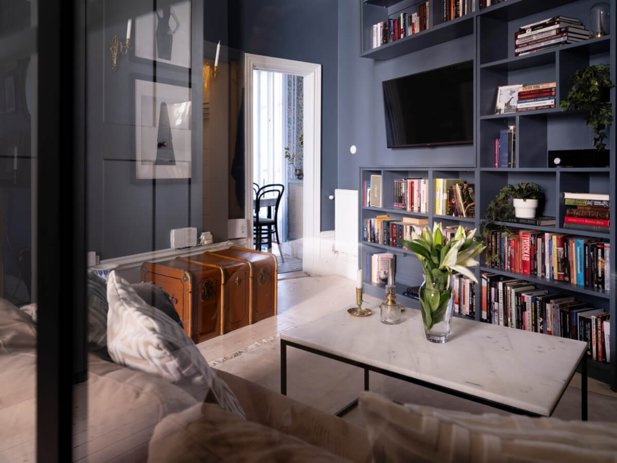A Classic Studio Apartment with an Industrial Glass Room Divider 5 swedish studio apartment with moody walls and built in shelf system nordroom