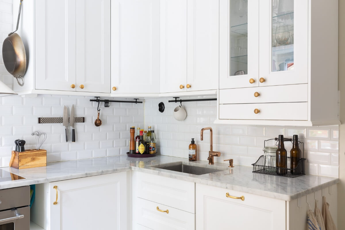 A Small and Bright Two-Bedroom Apartment in Stockholm 15 tiny classic kitchen with white cabinets and brass fittings