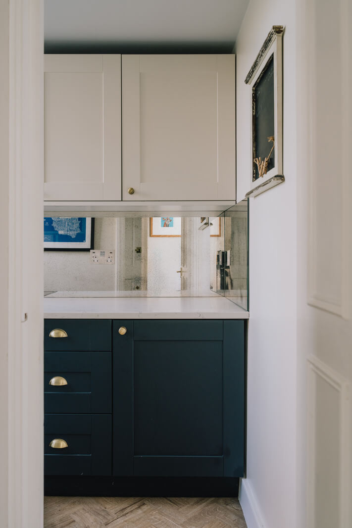 Why Everyone’s Adding Mirrors to Their Kitchens (And You Should Too) 2 tiny dark blue kitchen with mirror splashback