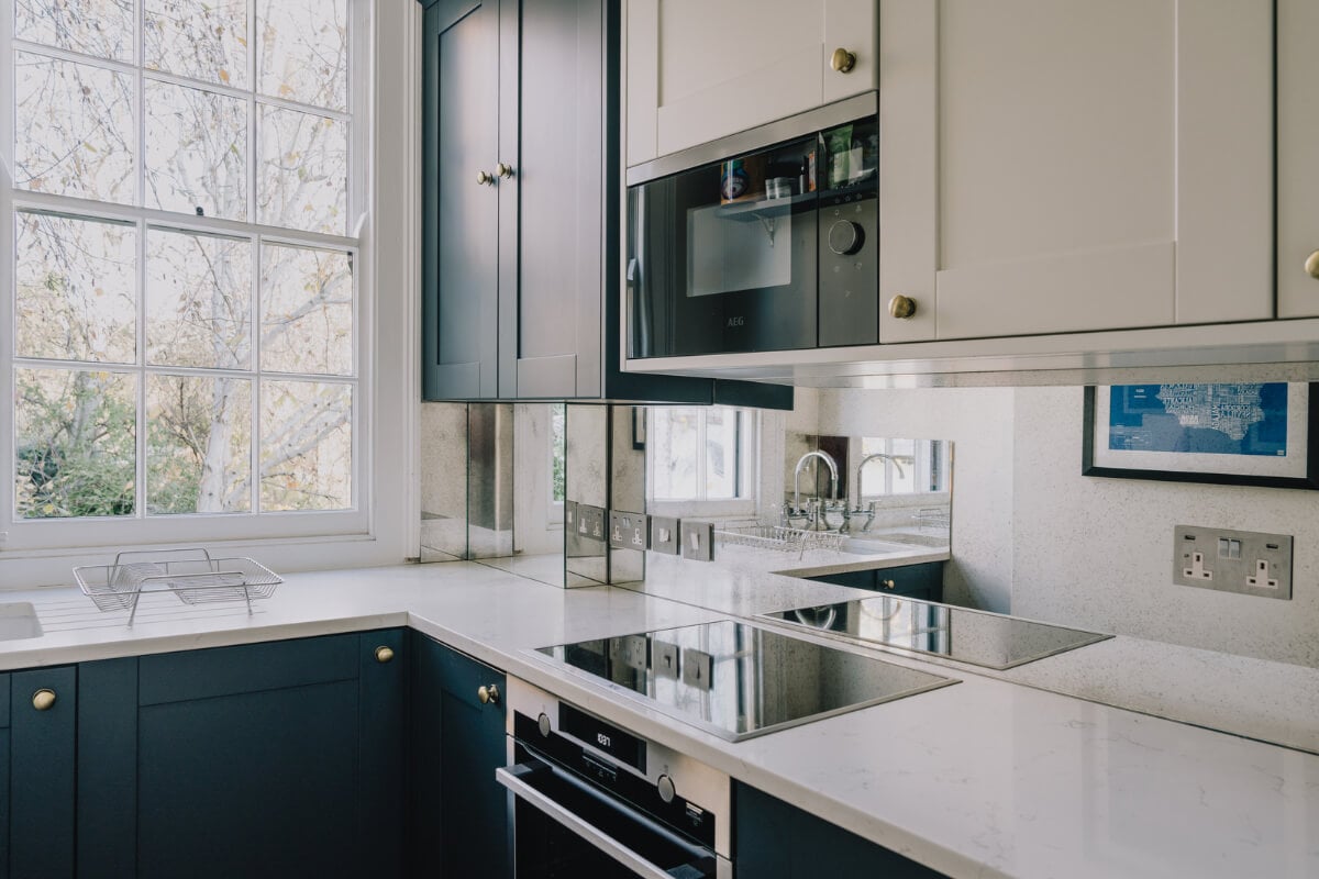 Countryside Charm in a London Apartment in a Former Ale House 11 tiny kitchen with dark blue cabinets and mirror backsplash nordroom