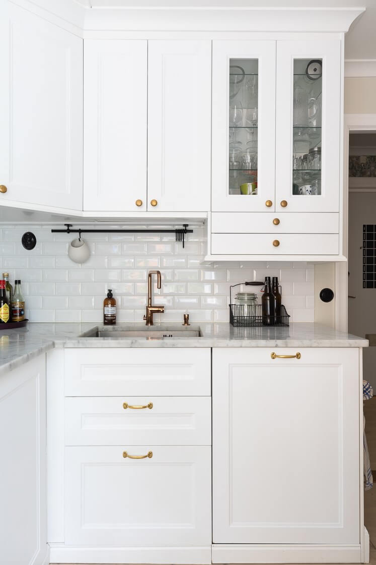 A Small and Bright Two-Bedroom Apartment in Stockholm 13 tiny white kitchen with marble countertop and brass fittings