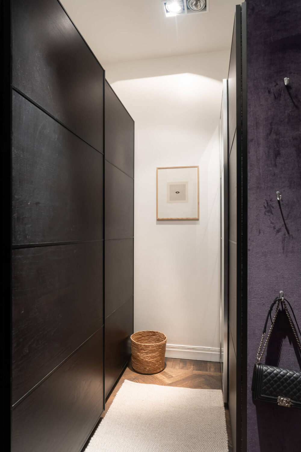 A Moody Color Palette in a Stylish One-Bedroom Apartment in Stockholm 17 walk in closet with black wardrobes