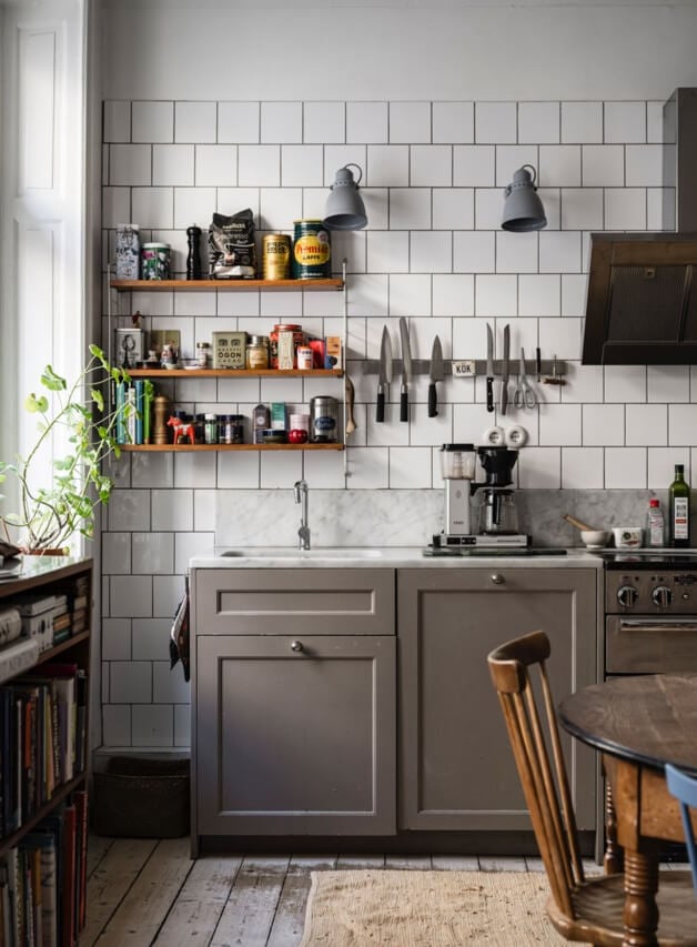Muted Tones, Art, and Books in a Charming Stockholm Apartment 7 white backsplash tiles and gray cabinets