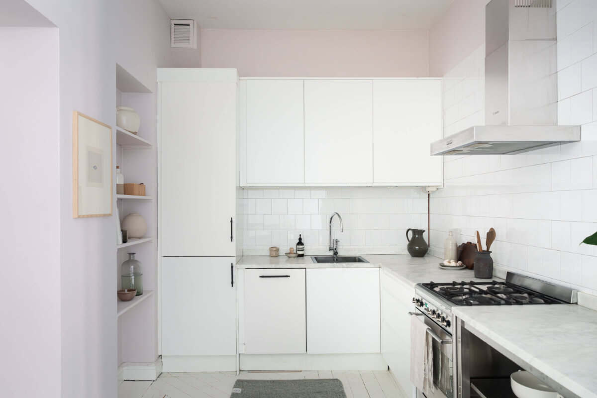 A Moody Color Palette in a Stylish One-Bedroom Apartment in Stockholm 15 white kitchen with white painted wooden floor