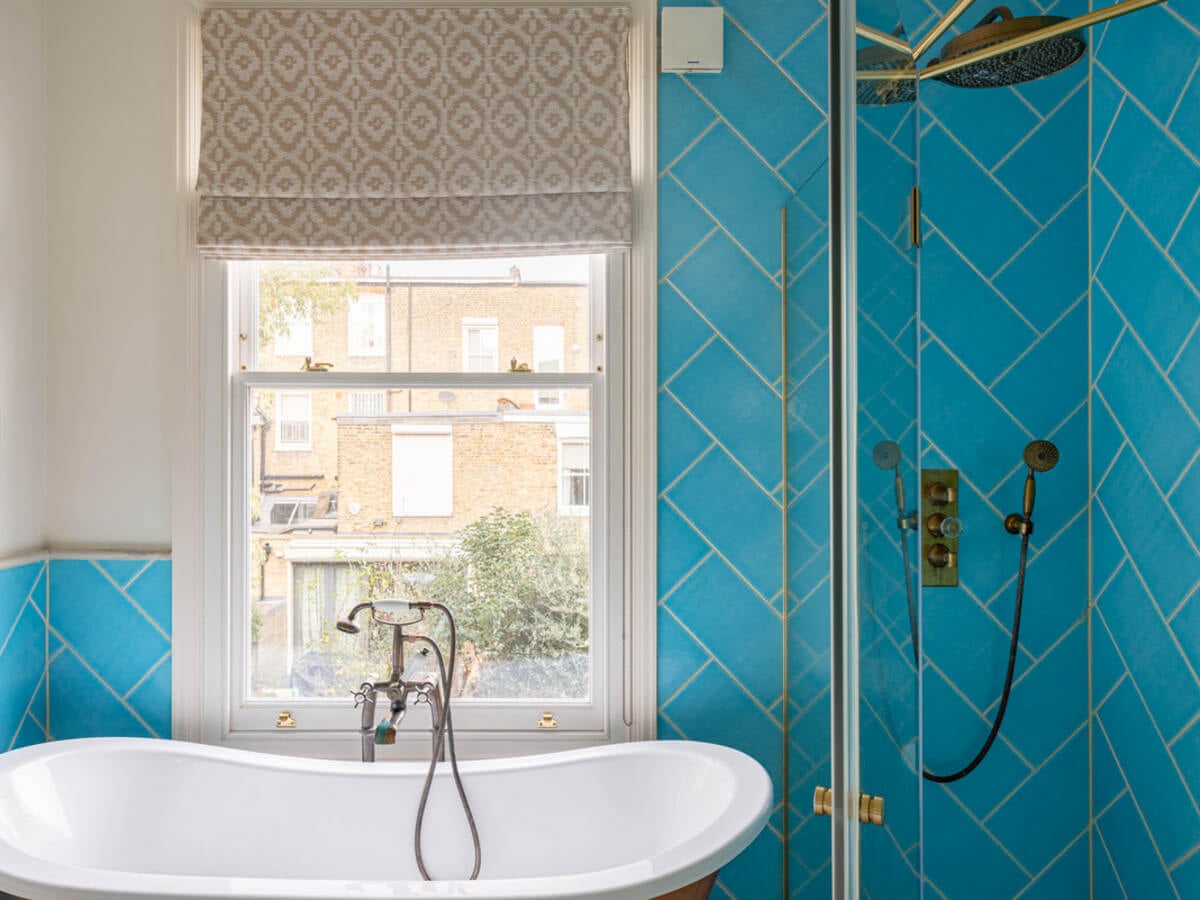 An Extended Family Home in London with Pink Crittall Doors 12 bathroom blue tiles freestanding bath in front of window