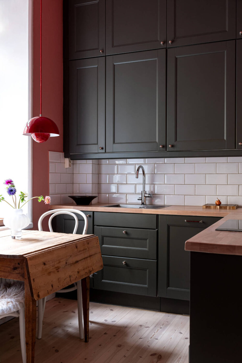 An Elegant Stockholm Apartment with a Pink and Black Kitchen 11 black kitchen cabinets pink wall wooden table