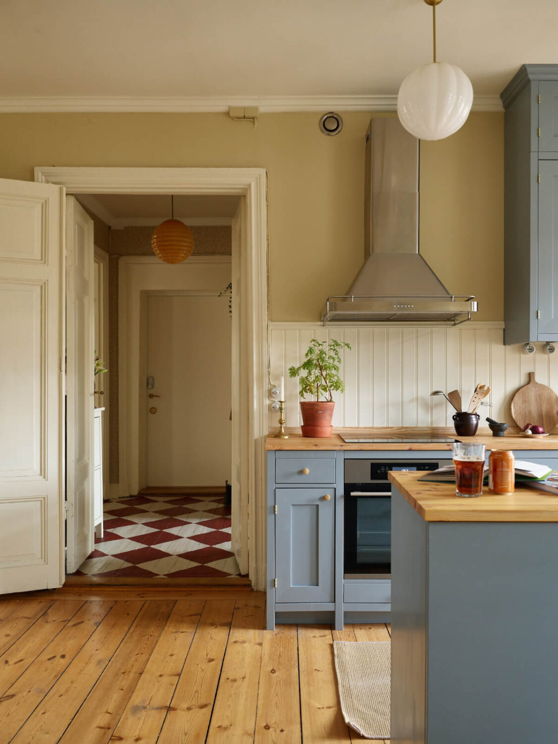 A Charming Historic Stockholm Apartment with a Blue Kitchen 6 blue kitchen wooden floor view to hall with checkerboard floor