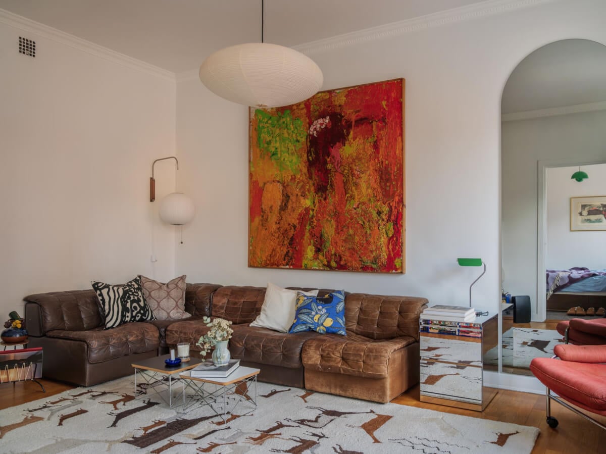 An Airy One-Bedroom Apartment with Art and A Yellow Kitchen 3 brown leather corner sofa