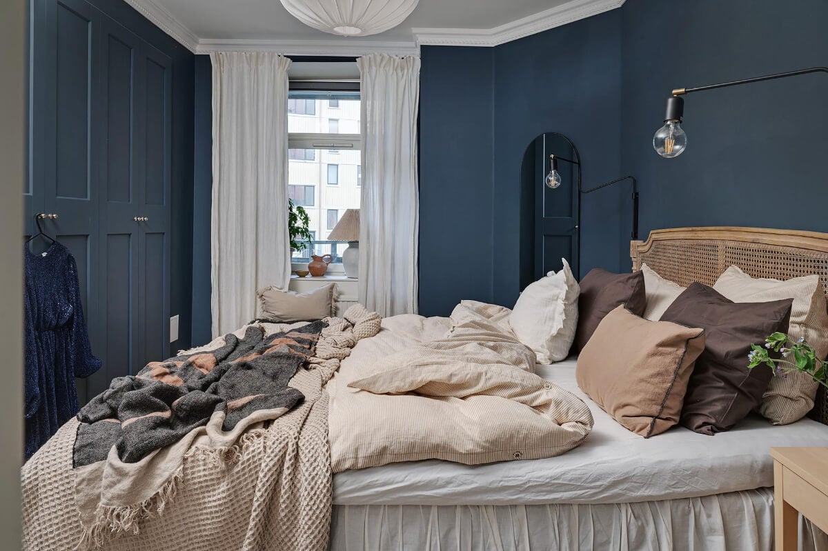 Warm and Inviting Rooms in a Renovated Swedish Apartment 19 dark blue bedroom built-in wardrobes cane headboard