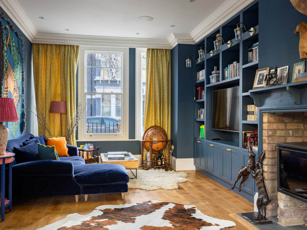An Extended Family Home in London with Pink Crittall Doors 4 dark blue living room built in bookshelves yellow curtains