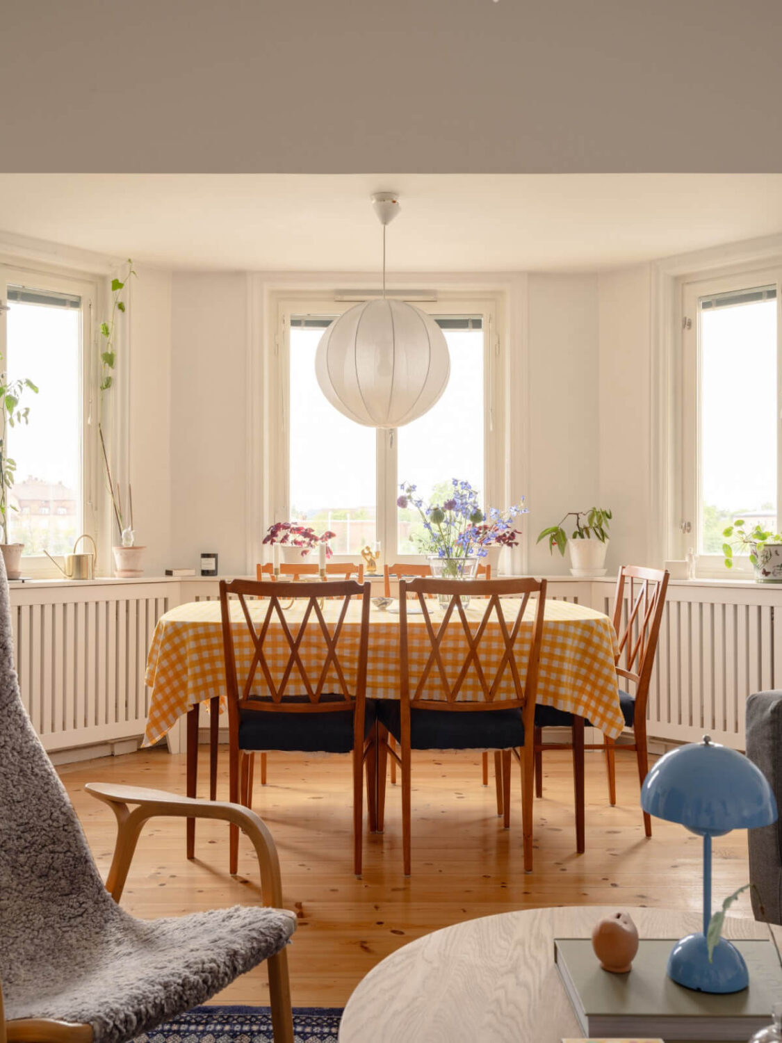 A Small Apartment with High Ceilings and a Large Bay Window 7 dining table in bay window yellow tablecloth