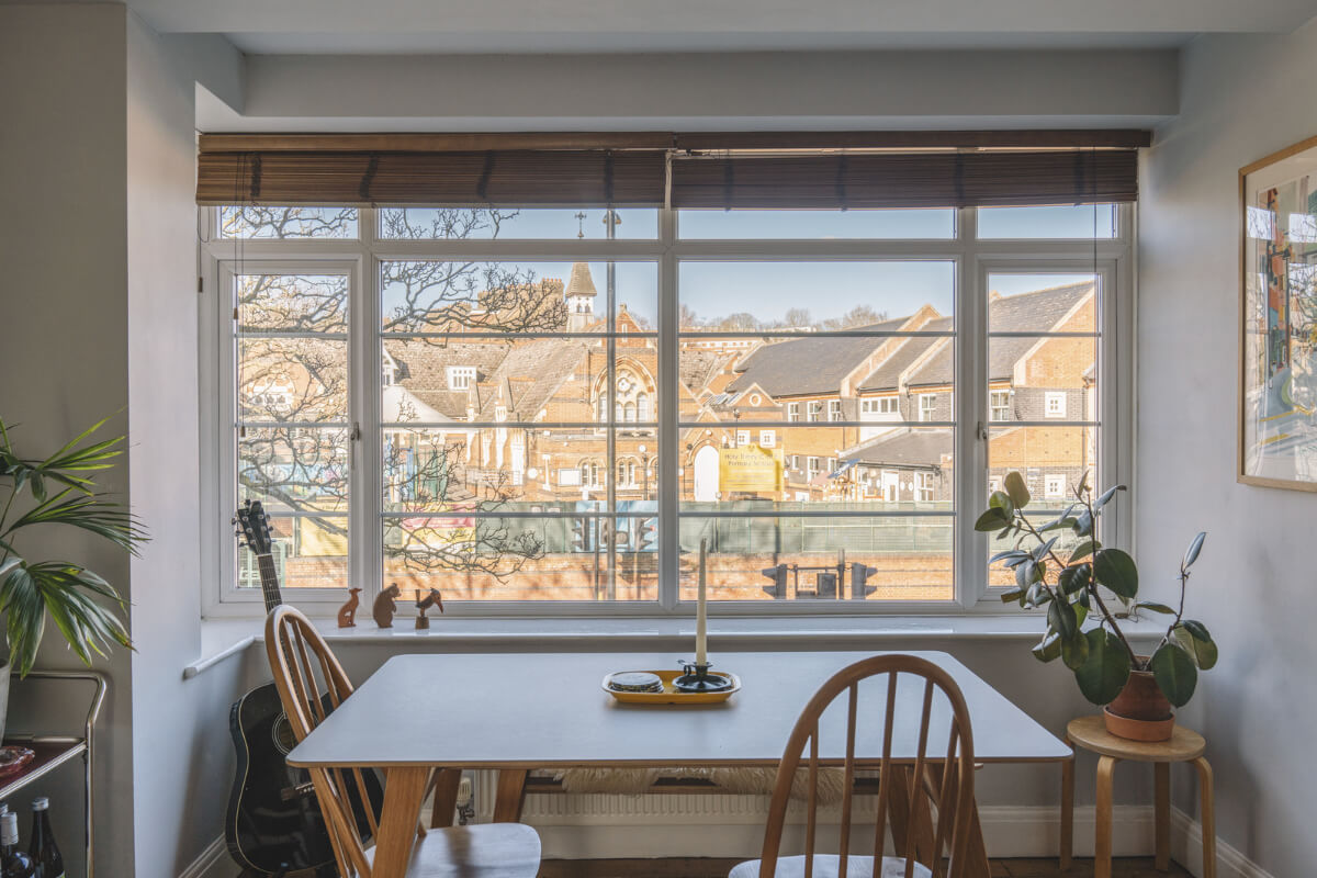 A London Apartment with a Pink and Green Kitchen 4 dining table in front of window