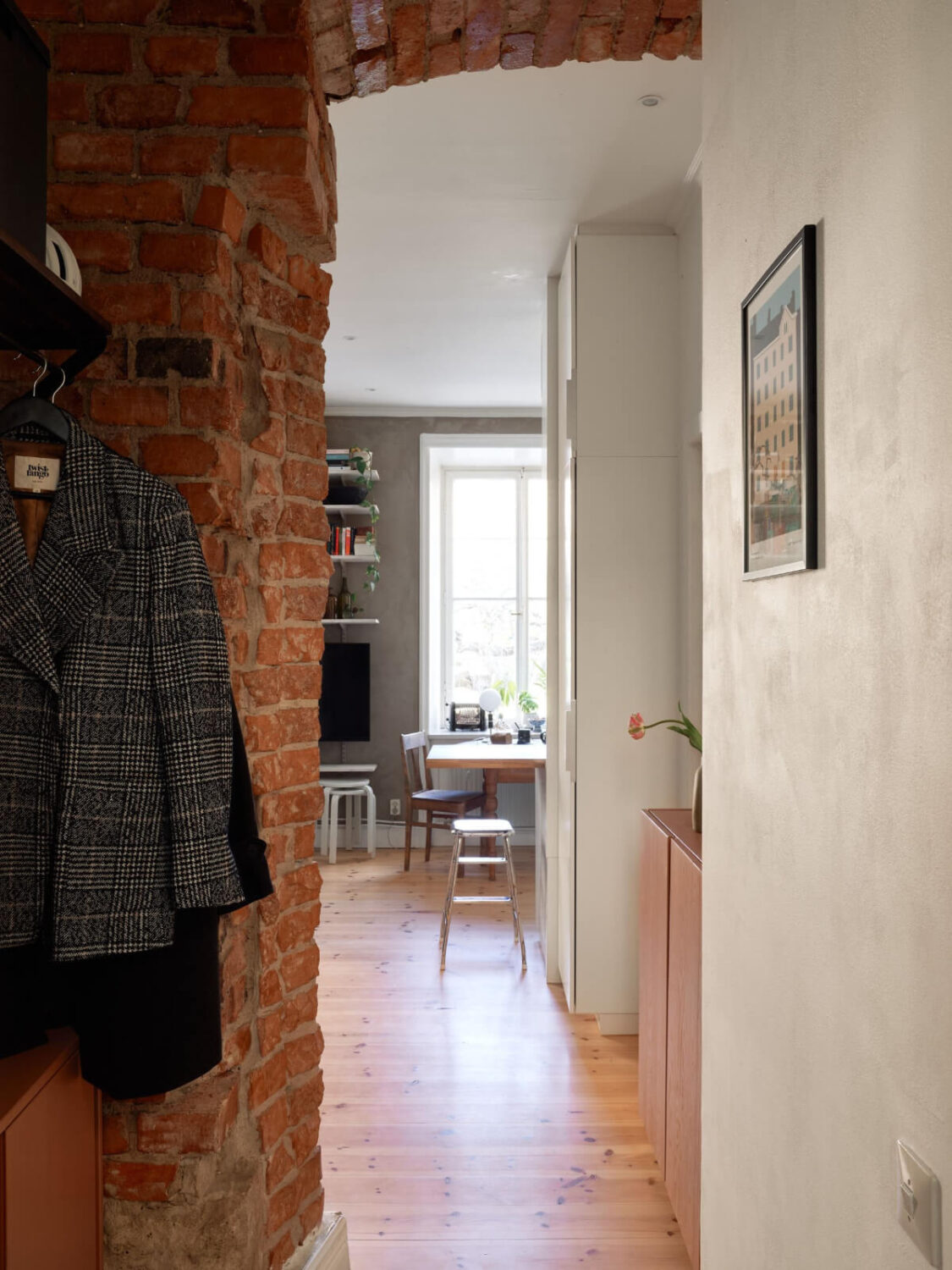 A Studio Apartment with Smart Storage Ideas and Exposed Brick 15 exposed brick doorway view into studio with wooden floor