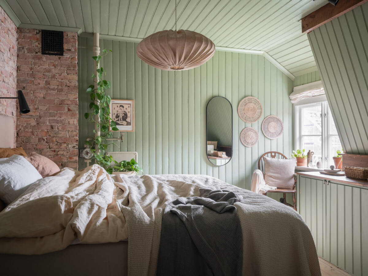 A Carefully Renovated Family Home in Sweden 27 green bedroom with exposed brick wall and slanted ceiling