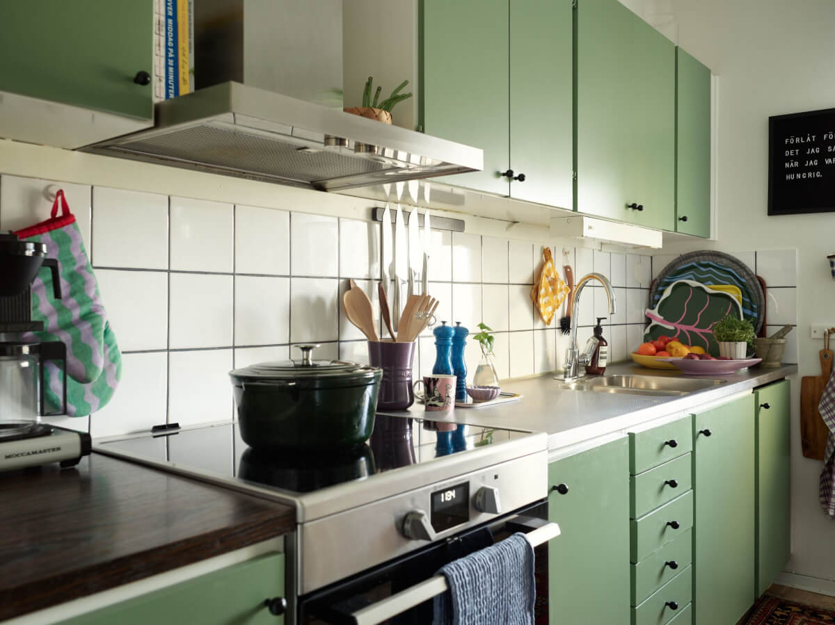 A Colorful Midcentury Apartment Filled with Art and Plants 11 green kitchen cabinets