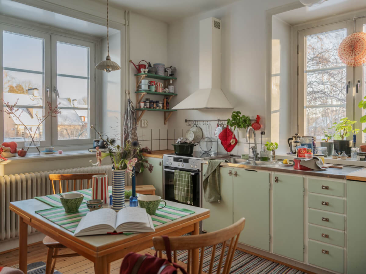 A Charming and Light-Filled Studio Apartment in Stockholm 8 green midcentury kitchen with wooden floor and square vintage table