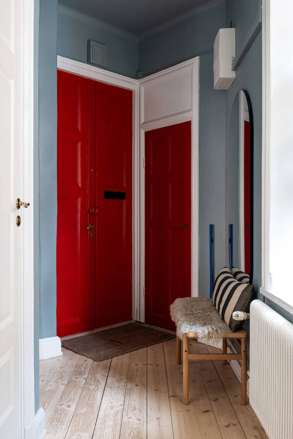 An Elegant Stockholm Apartment with a Pink and Black Kitchen 25 hall with bench red front door