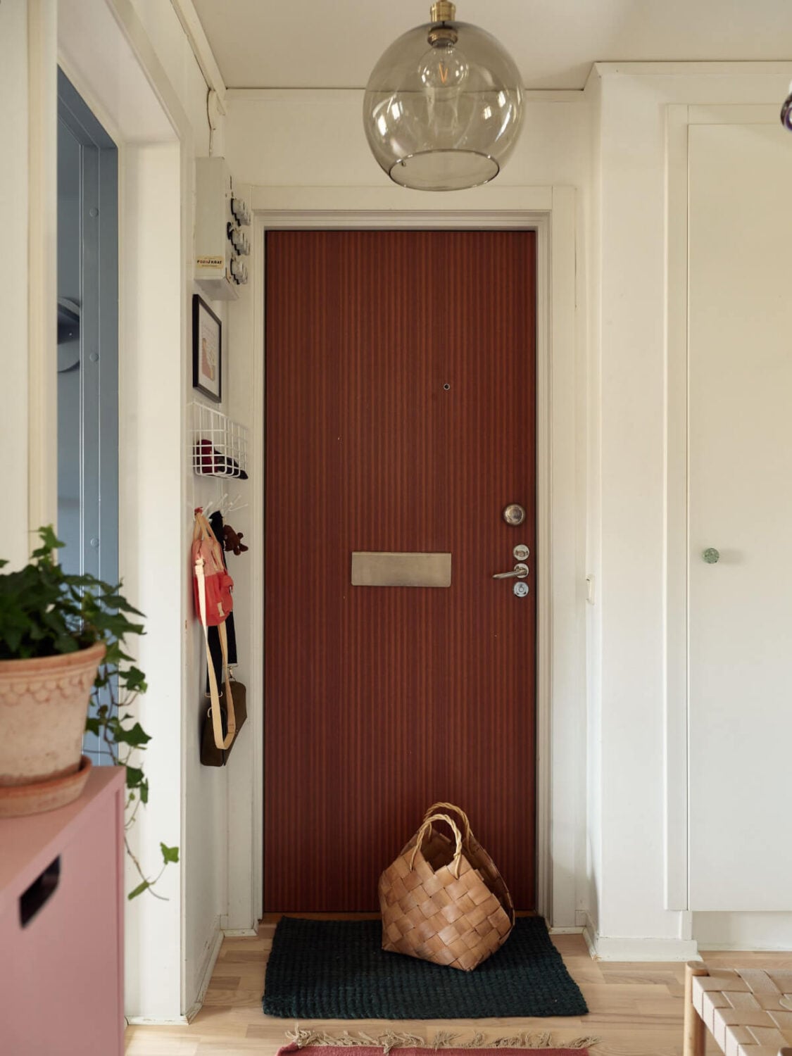 A Colorful Midcentury Apartment Filled with Art and Plants 22 hallway small storage by door