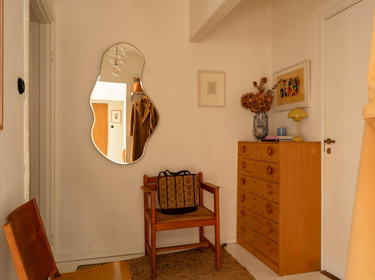 A Charming Midcentury Apartment with a Reading Room 27 hallway with wooden drawer and asymmetrical mirror A Charming Midcentury Apartment with a Reading Room