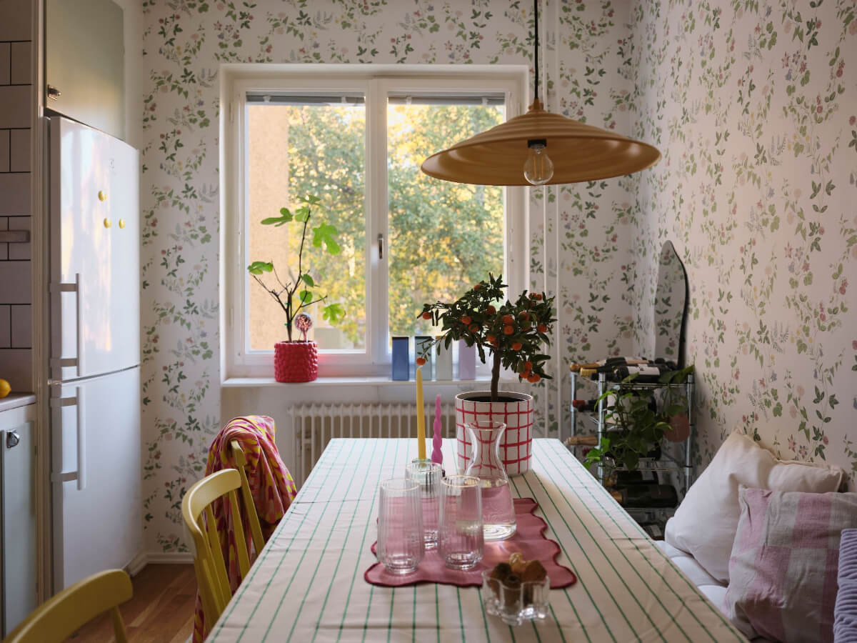 A Midcentury Swedish Apartment with Bright Color Accents 13 kitchen table dining with striped table cloth and floral wallpaper
