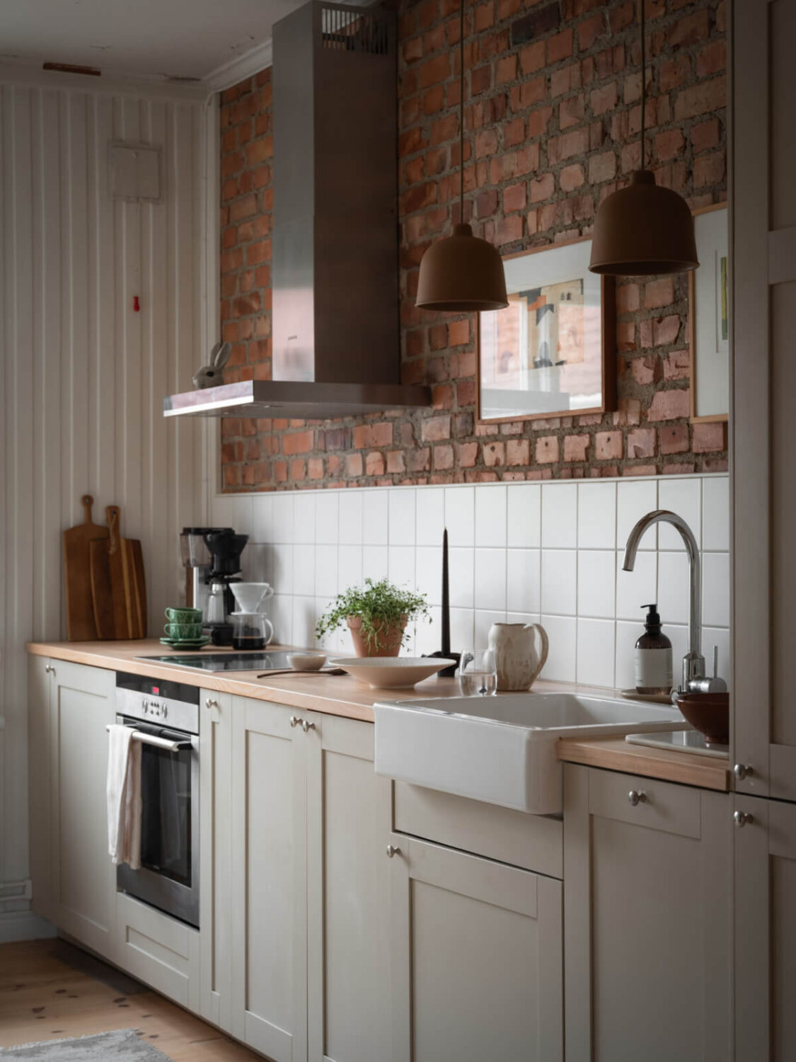 A Renovated Duplex Apartment with Exposed Brick Walls 7 kitchen with exposed brick wall and brown pendant lights nordroom