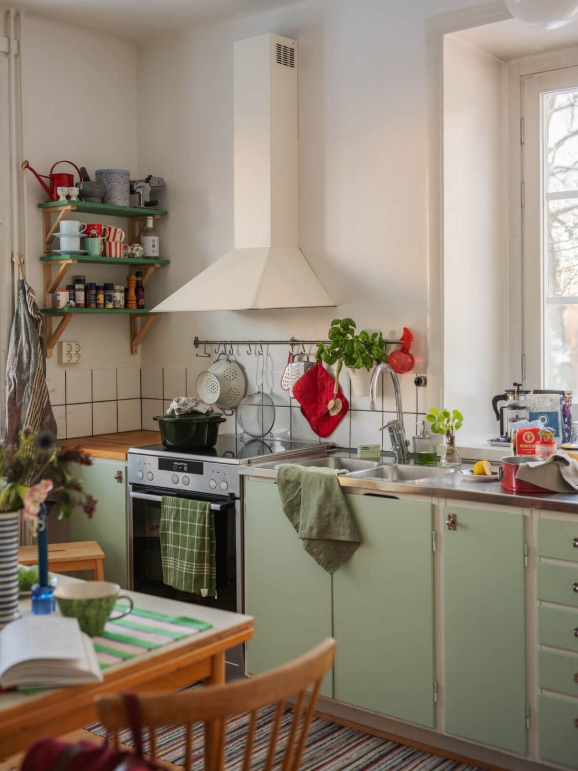 A Charming and Light-Filled Studio Apartment in Stockholm 12 kitchen with green cabinets and shelves