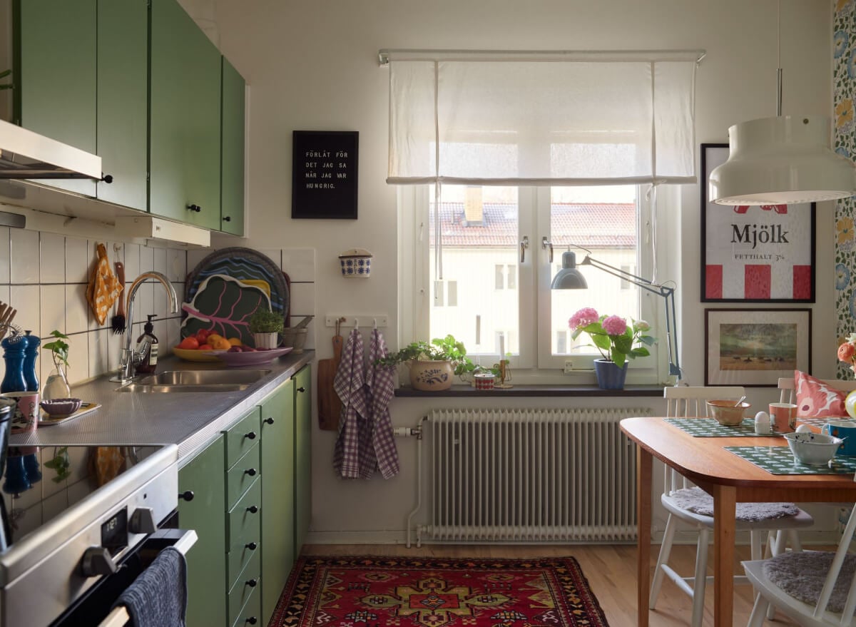 A Colorful Midcentury Apartment Filled with Art and Plants 10 light kitchen green cupboards dining table
