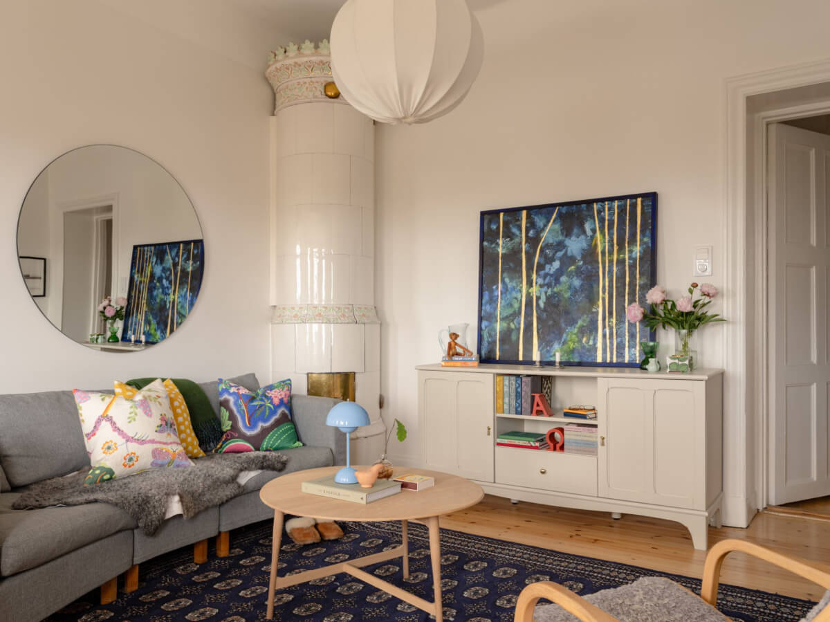 A Small Apartment with High Ceilings and a Large Bay Window 3 living room large blue rug round mirror fireplace