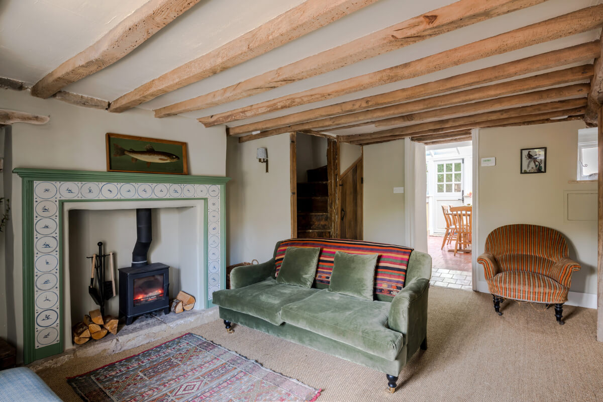 A Carefully Selected Color Palette in an 18th-Century English Cottage 1 living room low ceiling wooden beams fireplace and green couch