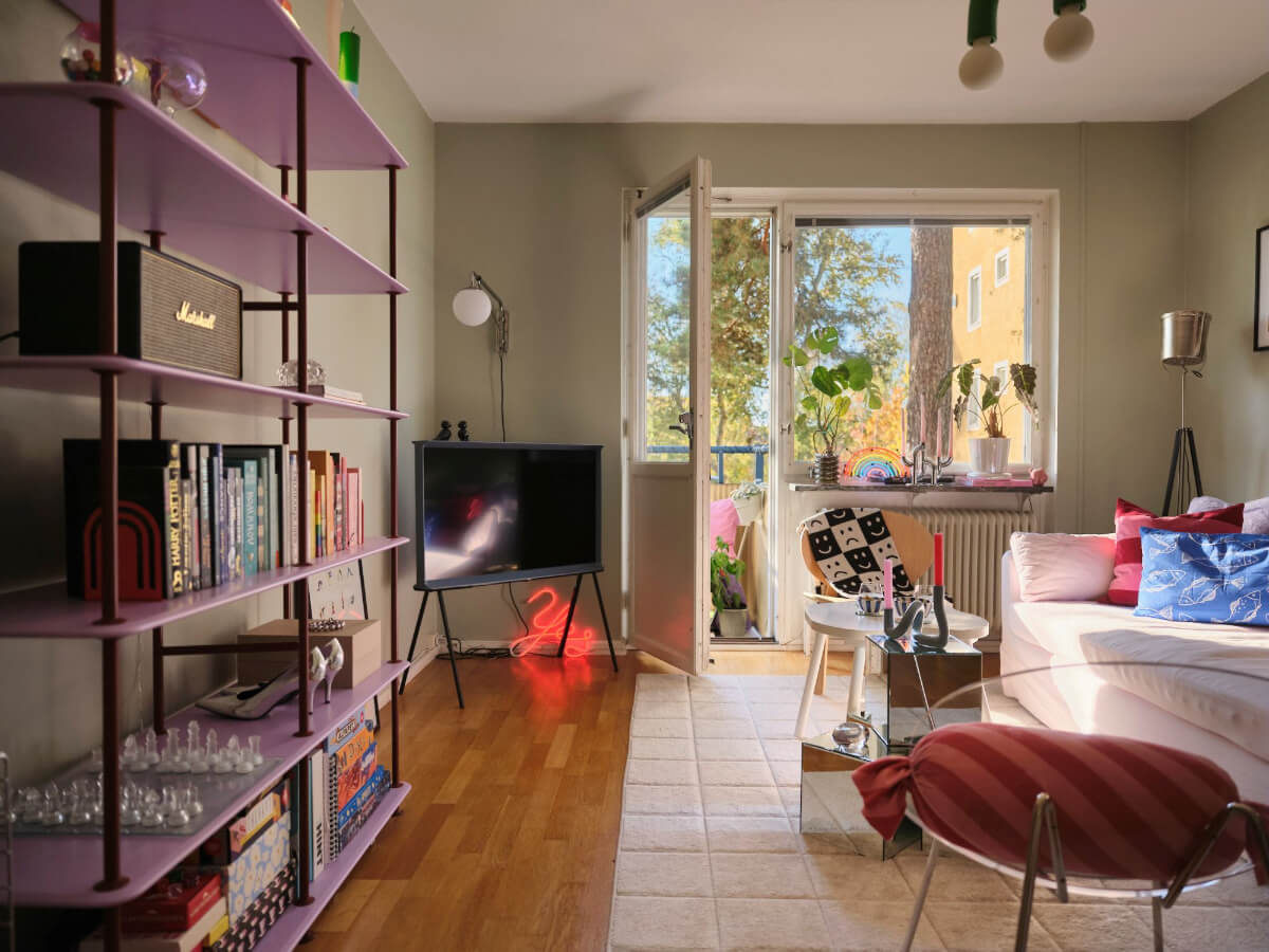 A Midcentury Swedish Apartment with Bright Color Accents 3 living room sage green walls purple bookshelves and colorful decor