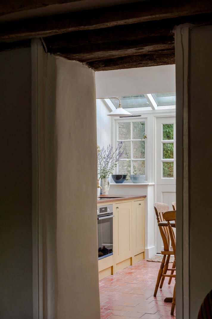A Carefully Selected Color Palette in an 18th-Century English Cottage 4 peek into ochre yellow kitchen with terracotta floor