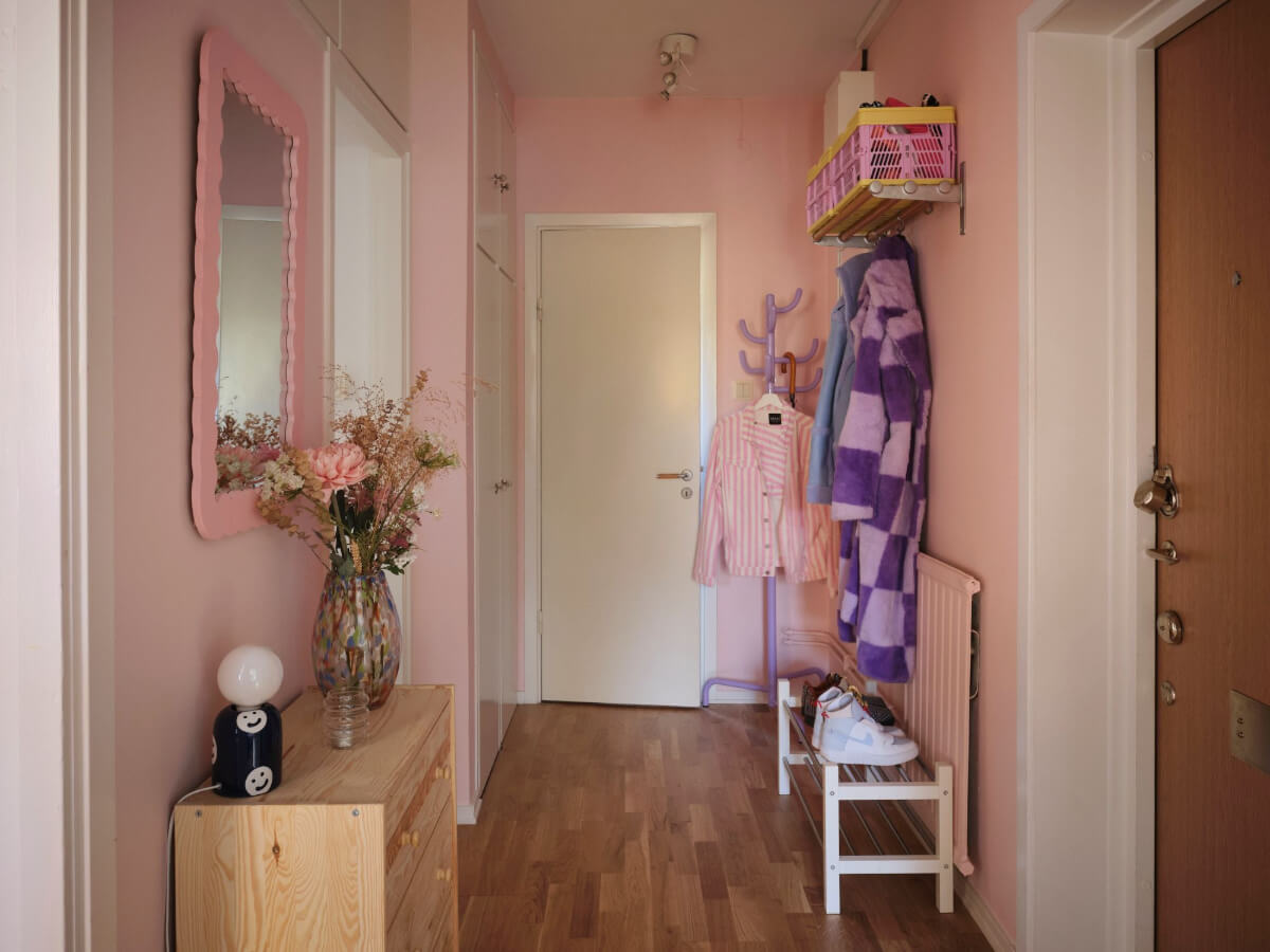 A Midcentury Swedish Apartment with Bright Color Accents 19 pink hallway with purple coat hanger