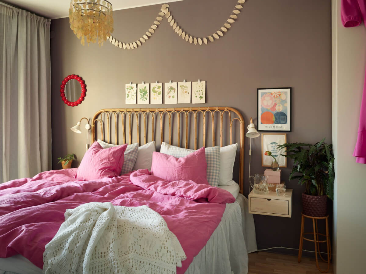 A Colorful Midcentury Apartment Filled with Art and Plants 15 plum colored bedroom with pink bedding and rattan bed