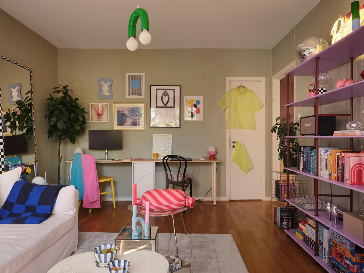 A Midcentury Swedish Apartment with Bright Color Accents 6 sage green living room with double desk and purple bookshelves